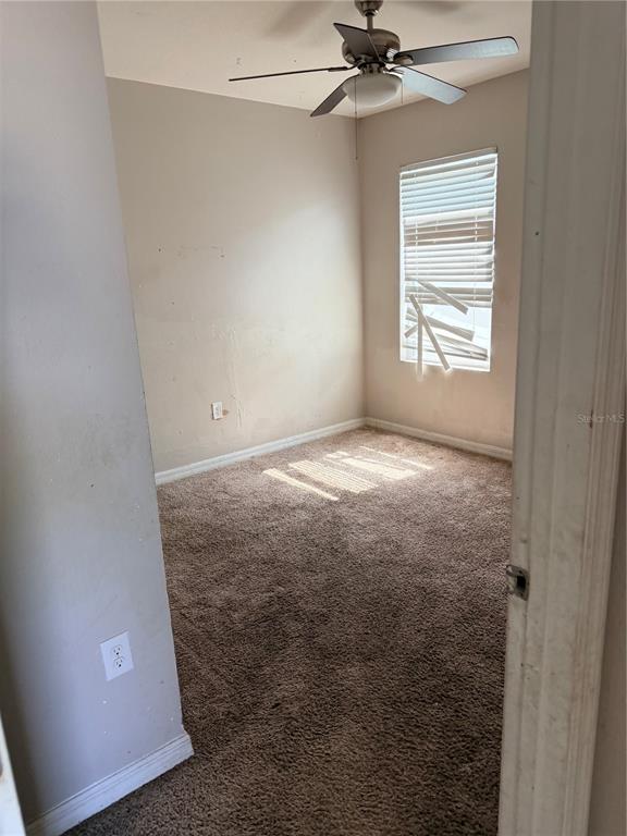 An empty bedroom features beige walls, brown carpeting, a ceiling fan, and damaged window blinds — 615 TRALEE LANE, AUBURNDALE, FL
