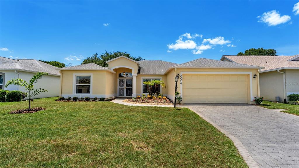 A single-story house with a beige stucco exterior, a two-car garage, and a landscaped yard — 6008 SWALLOW DRIVE, LAKELAND, FL