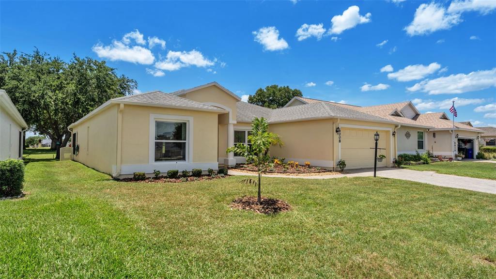 A single-story house with a beige stucco exterior, a two-car garage, and a front lawn — 6008 SWALLOW DRIVE, LAKELAND, FL