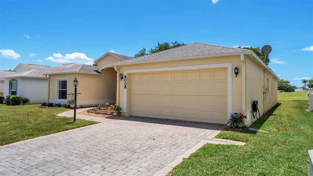 A single-story house with a yellow stucco exterior, a paved driveway, and a two-car garage — 6008 SWALLOW DRIVE, LAKELAND, FL