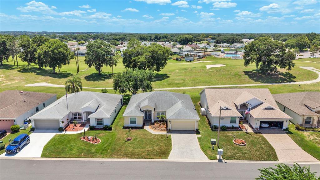 An aerial view shows three suburban houses with driveways facing a golf course — 6008 SWALLOW DRIVE, LAKELAND, FL