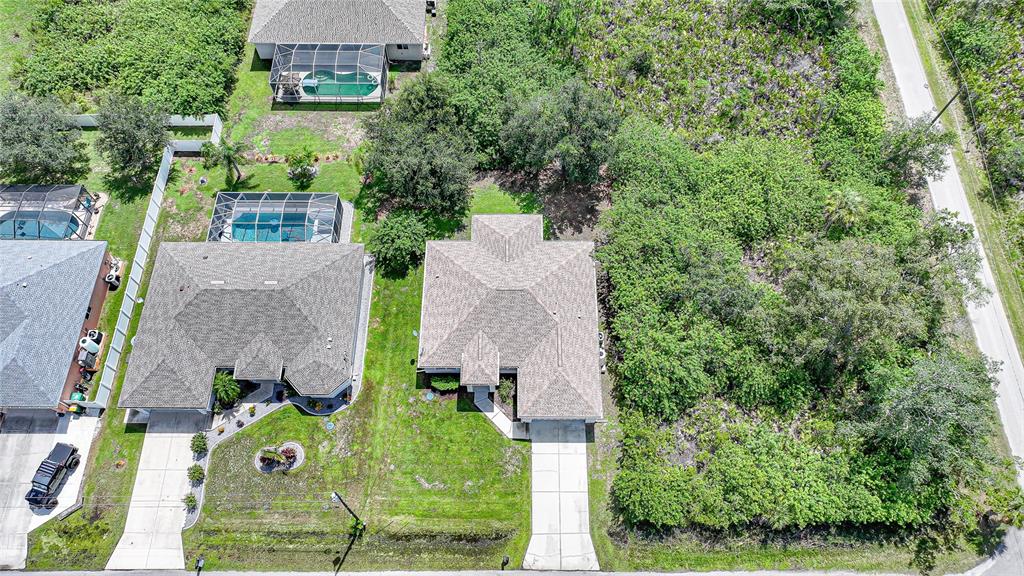 An aerial view shows two suburban houses with driveways and a large wooded lot nearby — 1516 WESTOVER STREET, PORT CHARLOTTE, FL