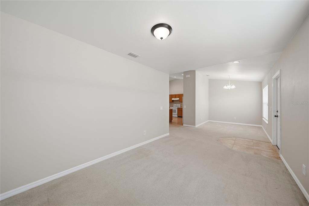 A carpeted living area leads to a dining space and a kitchen with wooden cabinets — 1516 WESTOVER STREET, PORT CHARLOTTE, FL