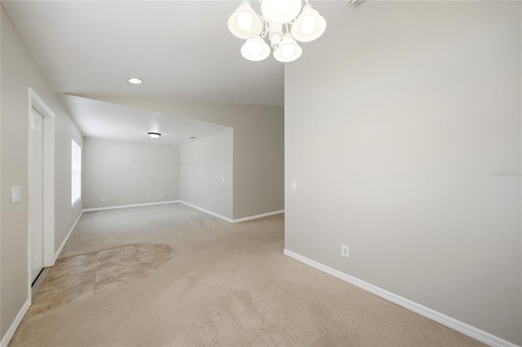 An interior view shows a carpeted room with a tile entryway and a chandelier — 1516 WESTOVER STREET, PORT CHARLOTTE, FL