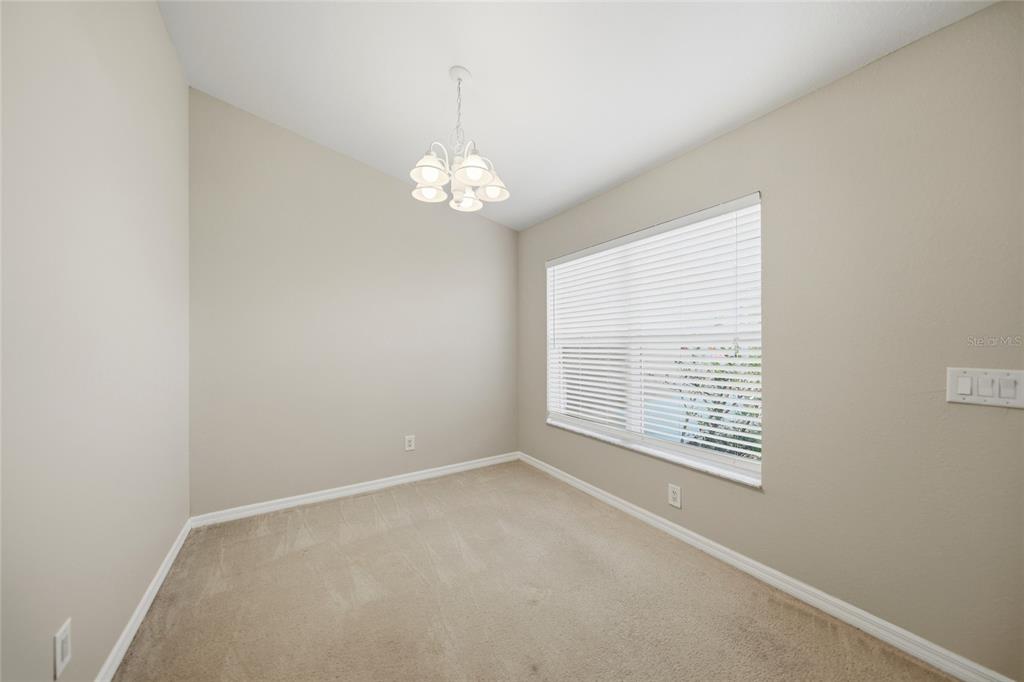 An empty room with beige carpet, light-colored walls, a chandelier, and a large window — 1516 WESTOVER STREET, PORT CHARLOTTE, FL