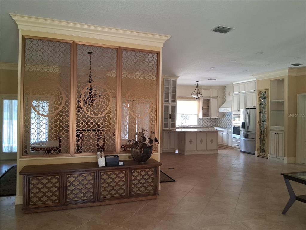 A kitchen with white cabinetry and a decorative gold-toned metal room divider in the foreground — 915 OLD WELCOME ROAD, LITHIA, FL