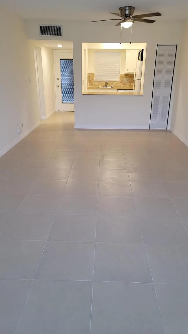 An open living area features light-colored tile flooring, a ceiling fan, and a kitchen pass-through — 6501 Winfield Boulevard # 40, Margate FL 33063, MARGATE, FL