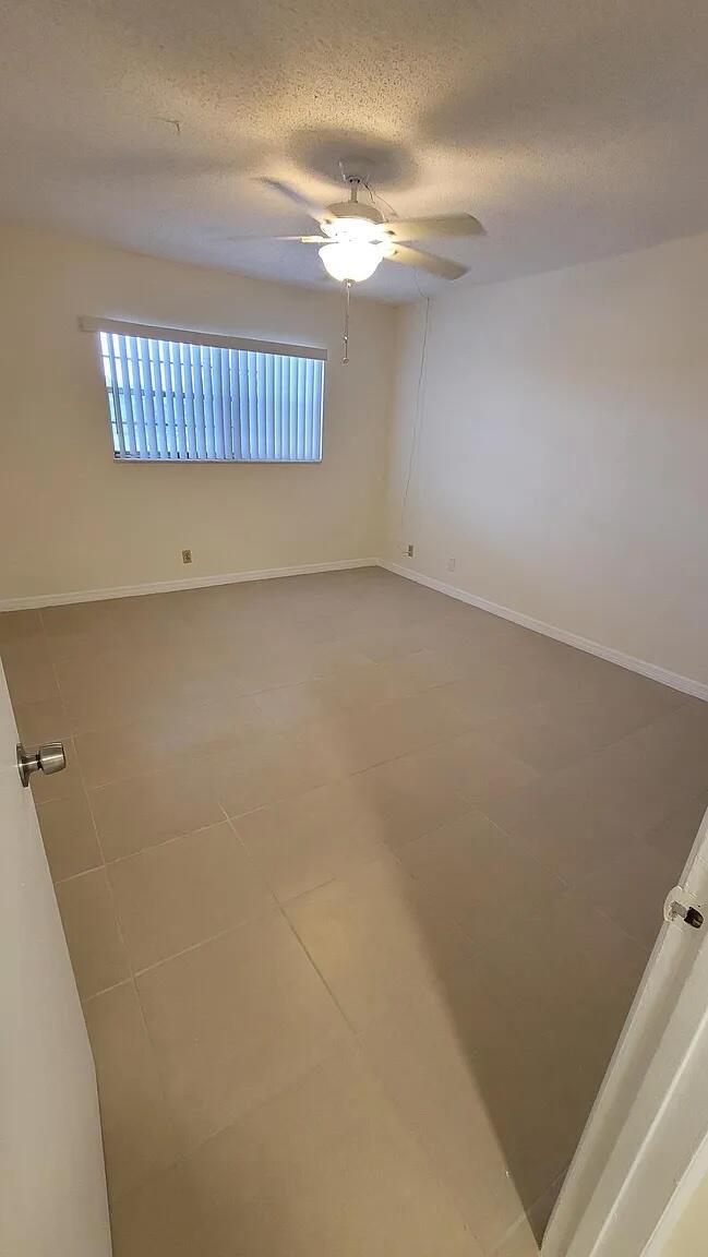 An empty bedroom features light-colored tile flooring, white walls, and a ceiling fan — 6501 Winfield Boulevard # 40, Margate FL 33063, MARGATE, FL
