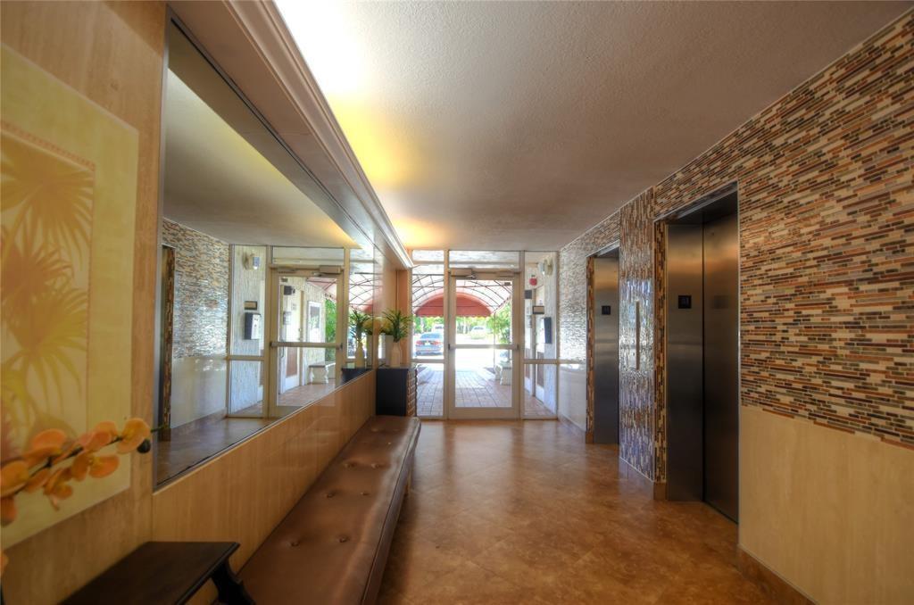 A building lobby features a long bench, a large mirror, and stainless steel elevator doors — 1391 S Ocean Boulevard # 204, Pompano Beach FL 33062, POMPANO BEACH, FL