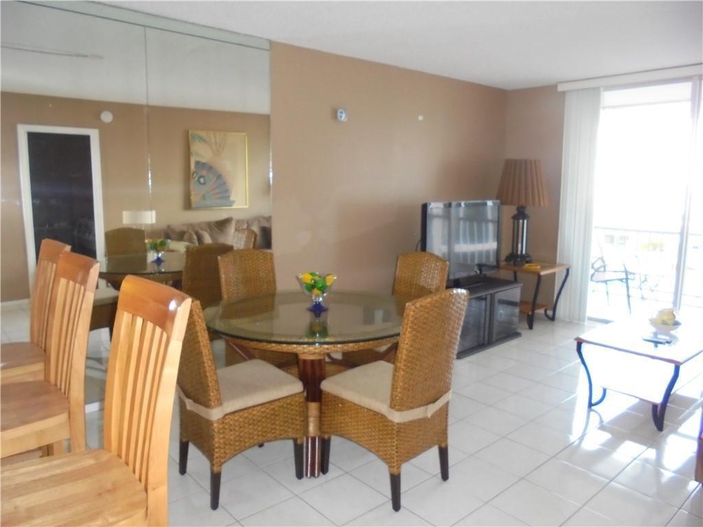 A dining area with a glass table and wicker chairs sits before a mirrored wall — 1391 S Ocean Boulevard # 204, Pompano Beach FL 33062, POMPANO BEACH, FL
