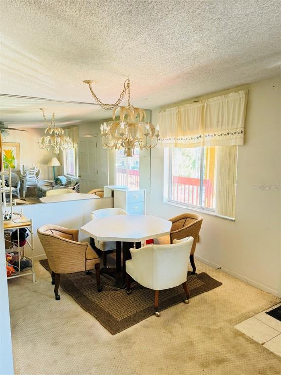 A dining area features a white octagonal table, four chairs, and a decorative chandelier — 400 EL CAMINO DRIVE UNIT 223, WINTER HAVEN, FL