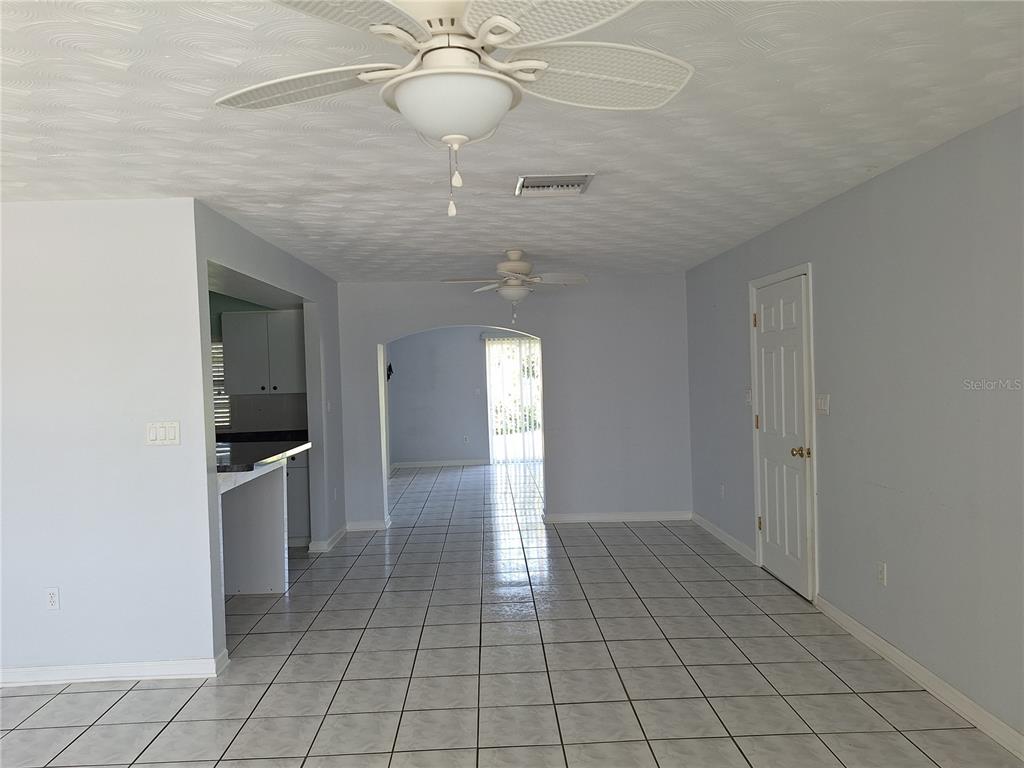 An interior view shows a tiled living area with two ceiling fans and an arched doorway — 22191 NEW ROCHELLE AVENUE, PORT CHARLOTTE, FL