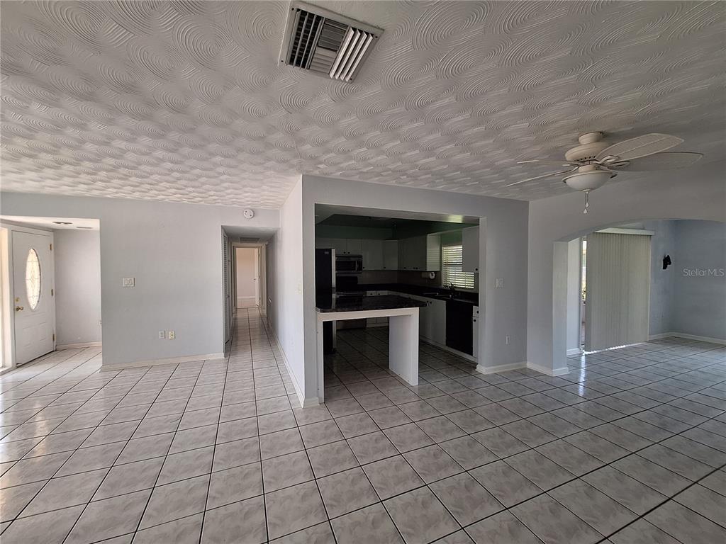 An open-concept living area features a tiled floor, a kitchen island, and a ceiling fan — 22191 NEW ROCHELLE AVENUE, PORT CHARLOTTE, FL