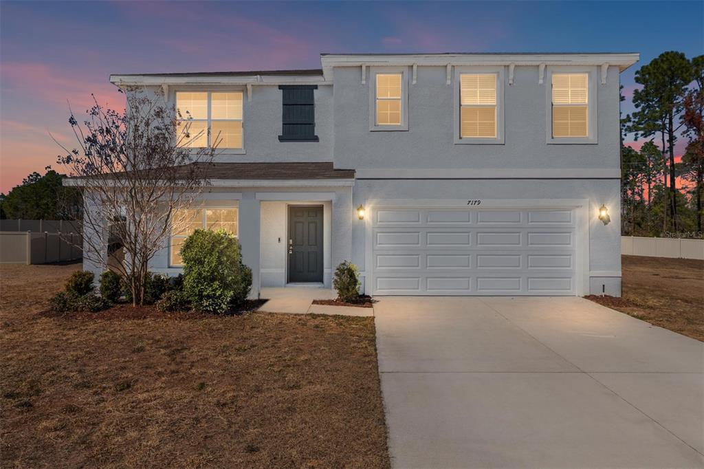 A two-story house with a white stucco exterior, a two-car garage, and a concrete driveway — 7179 SW 135TH PLACE, OCALA, FL