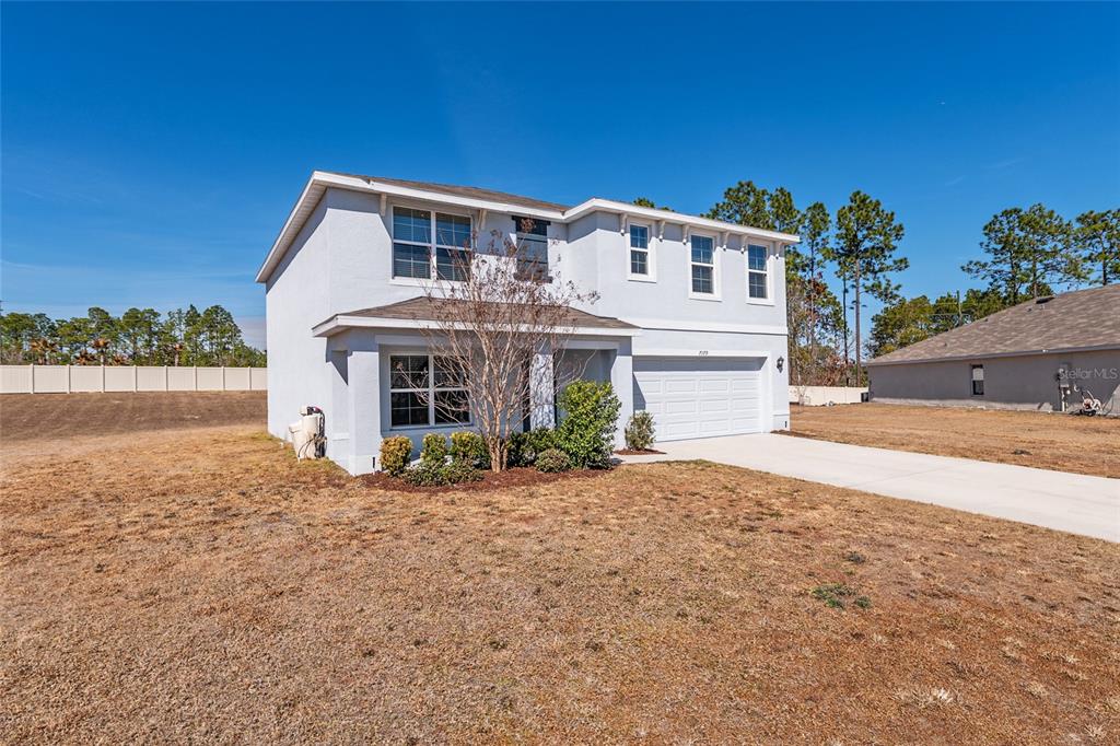 A two-story, light-colored suburban house with a two-car garage and a dry, grassy yard — 7179 SW 135TH PLACE, OCALA, FL