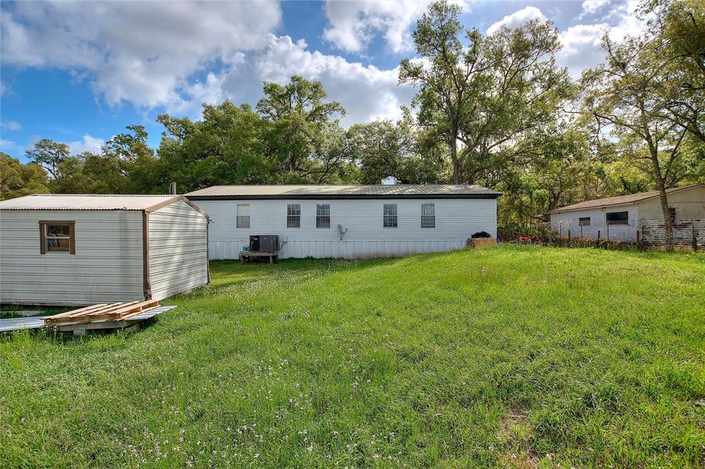 A mobile home and a shed sit on a grassy lot surrounded by mature trees — 3309 COOPER ROAD, PLANT CITY, FL