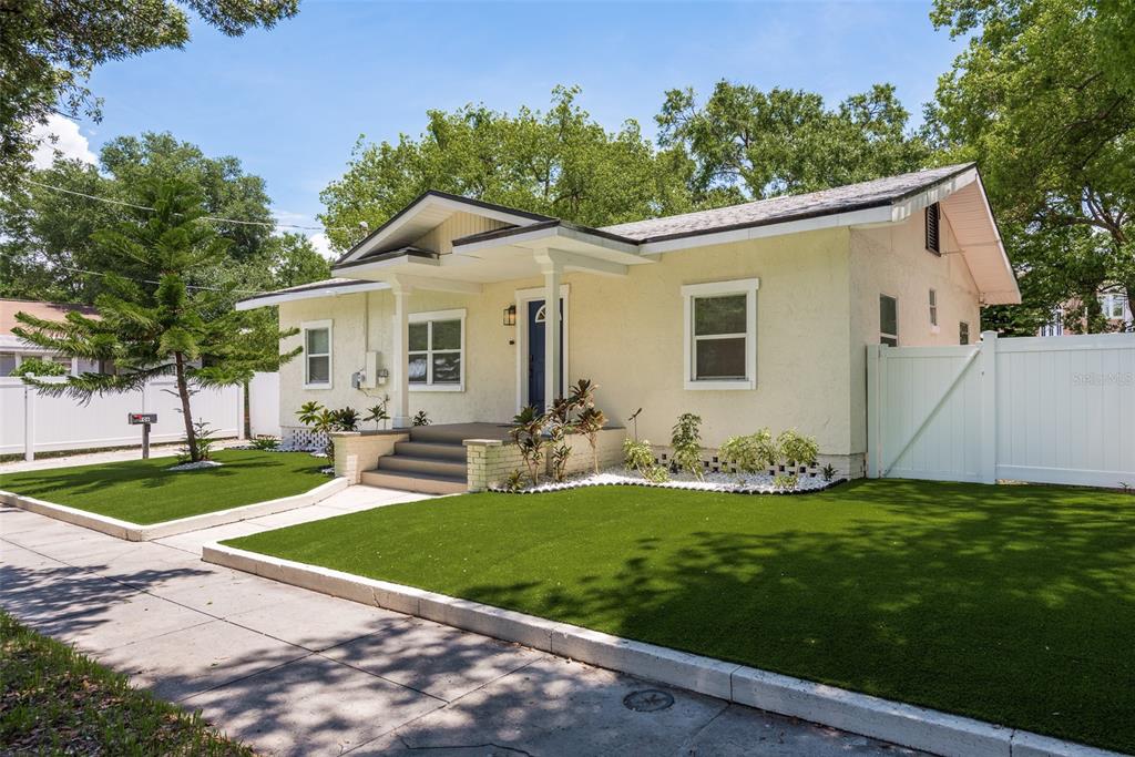 A single-story house with light yellow stucco siding, a front porch, and artificial turf lawn — 206 W WARREN AVENUE, TAMPA, FL