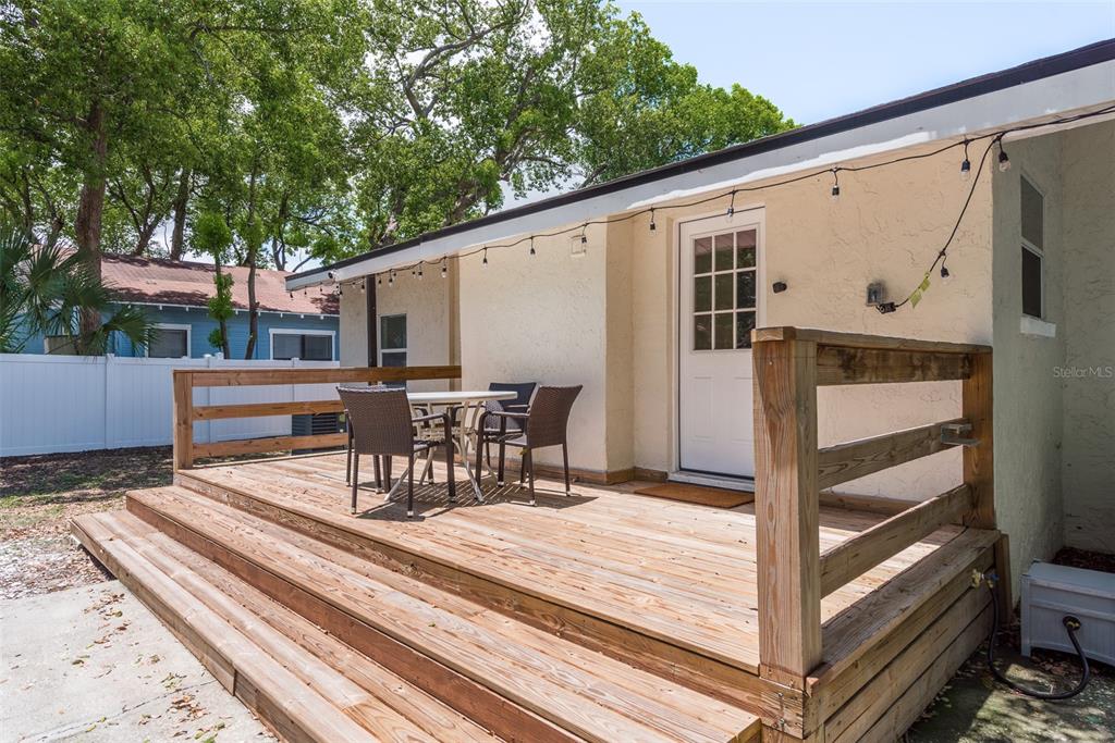 A wooden deck with a table and chairs sits outside a house with string lights — 206 W WARREN AVENUE, TAMPA, FL