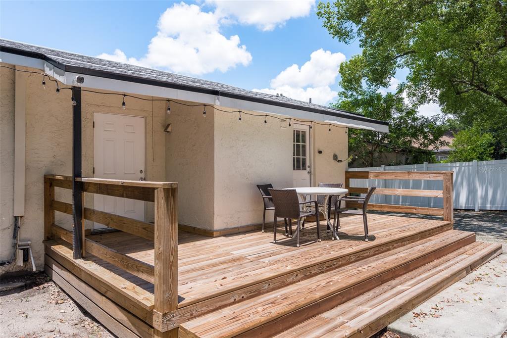 A wooden deck with a patio table and chairs sits outside a house with two doors — 206 W WARREN AVENUE, TAMPA, FL