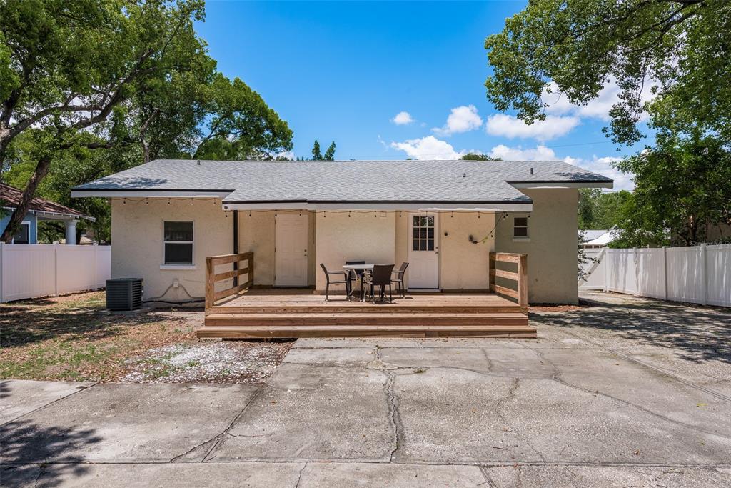 The exterior of a single-story house features a wooden deck, two doors, and a concrete driveway — 206 W WARREN AVENUE, TAMPA, FL