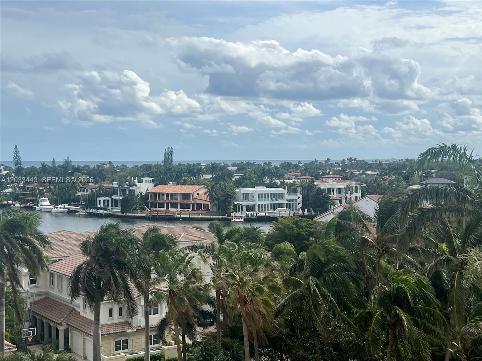 An elevated view shows waterfront houses, palm trees, and a canal under a cloudy sky — 21050 Point Pl # 702, Aventura FL 33180, AVENTURA, FL