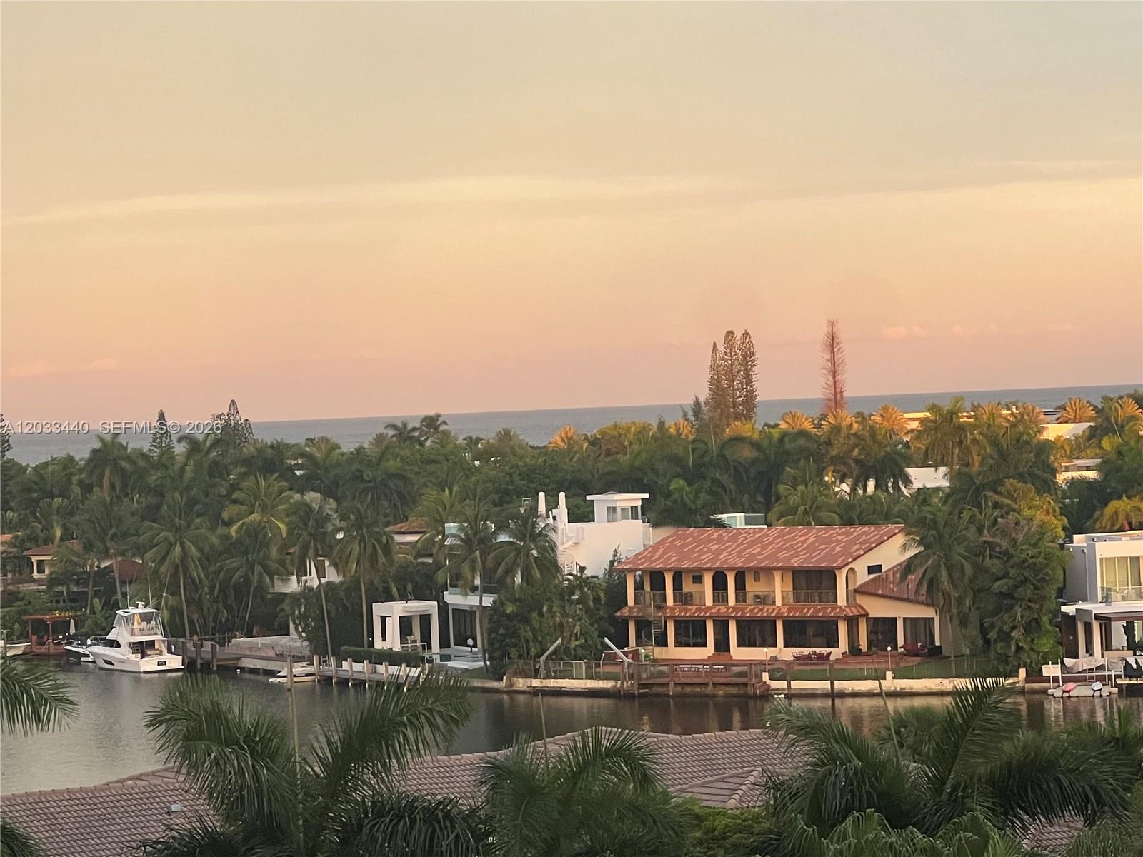 An aerial view shows waterfront homes with palm trees, a boat, and the ocean beyond — 21050 Point Pl # 702, Aventura FL 33180, AVENTURA, FL