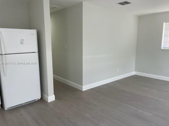 A white refrigerator stands in a room with light gray walls and wood-look flooring — FORT LAUDERDALE, FL