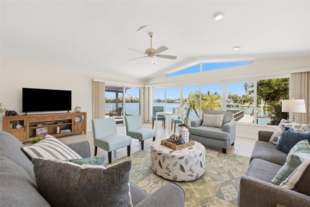 A living room with a vaulted ceiling, gray sofas, and large windows overlooking the water — 3666 BELLE VISTA DRIVE E, ST PETERSBURG, FL