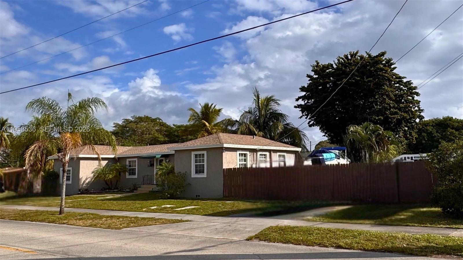 A single-story house with a brown fence and palm trees sits on a corner lot — 1825 N 24th Ave, Hollywood FL 33020, HOLLYWOOD, FL