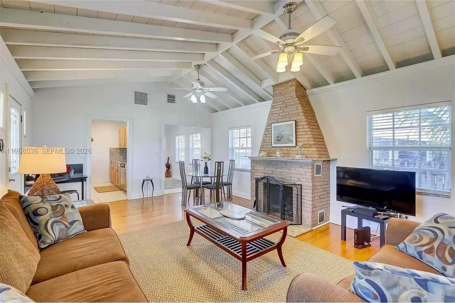 A living room features a vaulted ceiling, a brick fireplace, and hardwood floors — 1825 N 24th Ave, Hollywood FL 33020, HOLLYWOOD, FL