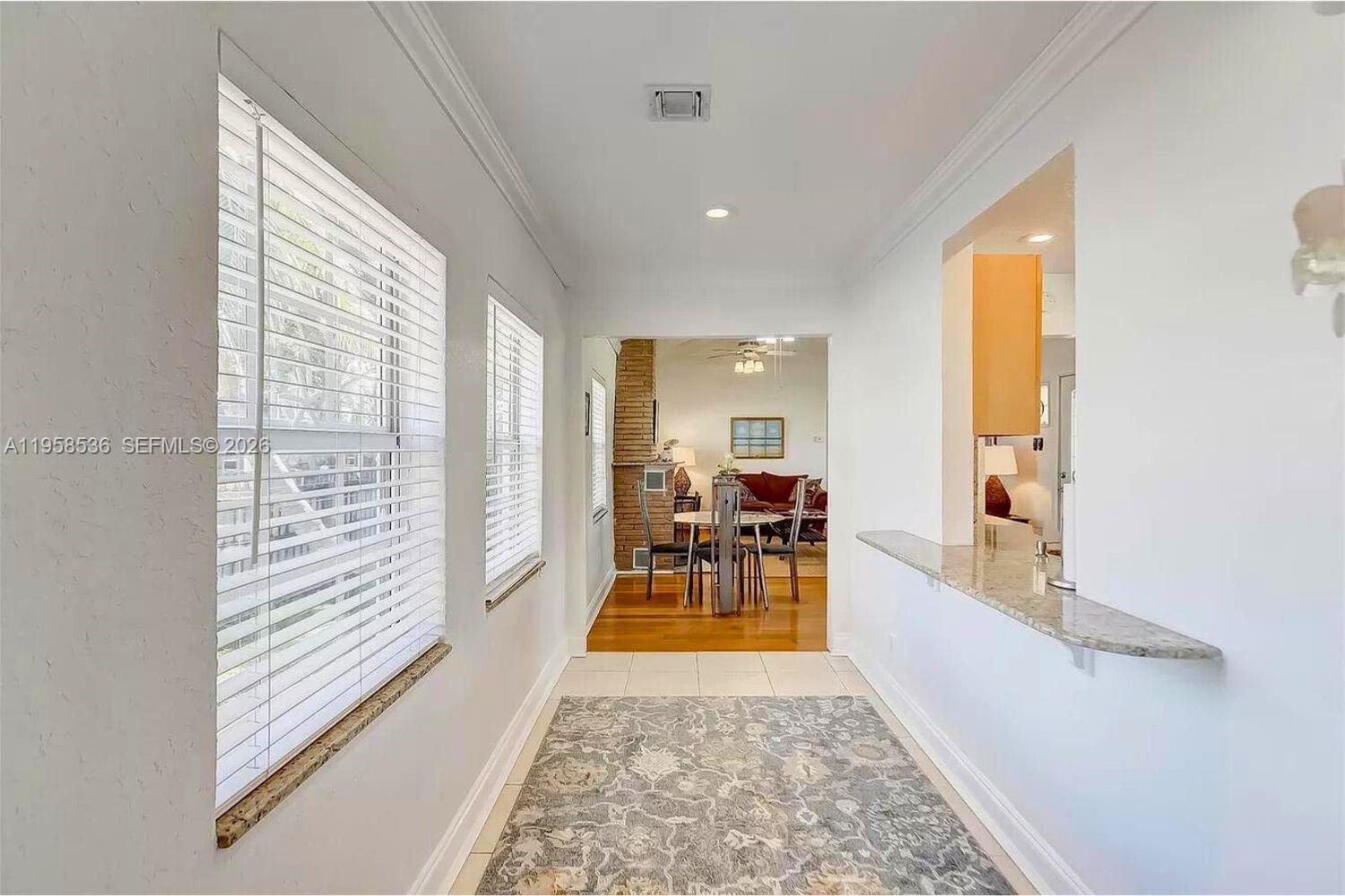 A hallway with tile floors and a rug leads to a dining area — 1825 N 24th Ave, Hollywood FL 33020, HOLLYWOOD, FL