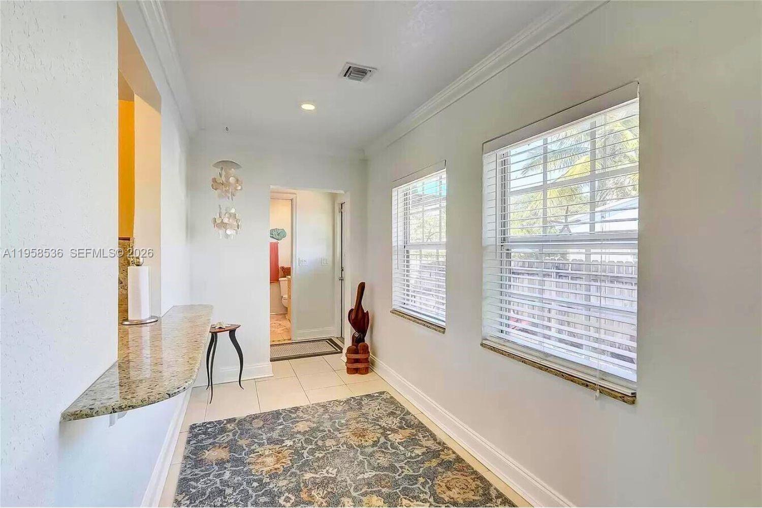 A hallway features a granite counter, tile flooring, a patterned rug, and two windows — 1825 N 24th Ave, Hollywood FL 33020, HOLLYWOOD, FL