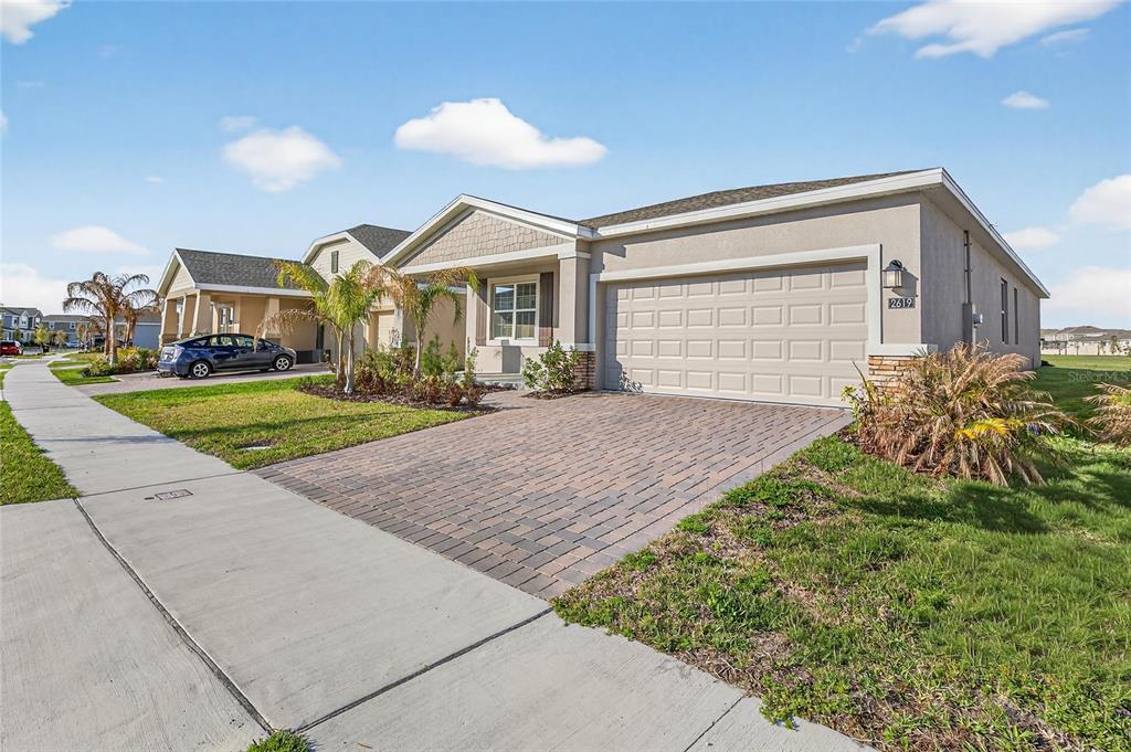 A single-story suburban house with a paved driveway, two-car garage, and a small front lawn — 2619 PEACE OF MIND AVENUE, KISSIMMEE, FL