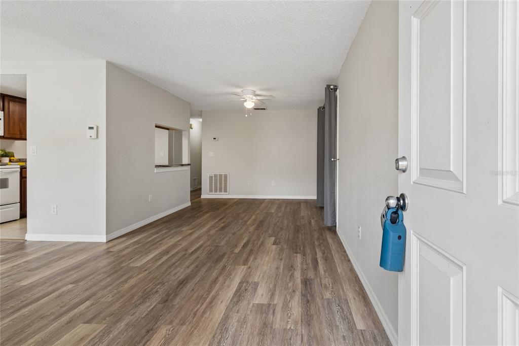 An interior view of a living room with wood-look flooring and a ceiling fan — 133 SABAL COURT UNIT G, OLDSMAR, FL