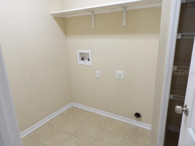 A laundry room with tile flooring, a wall-mounted shelf, and utility hookups for appliances — 12669 BELCROFT DRIVE, RIVERVIEW, FL