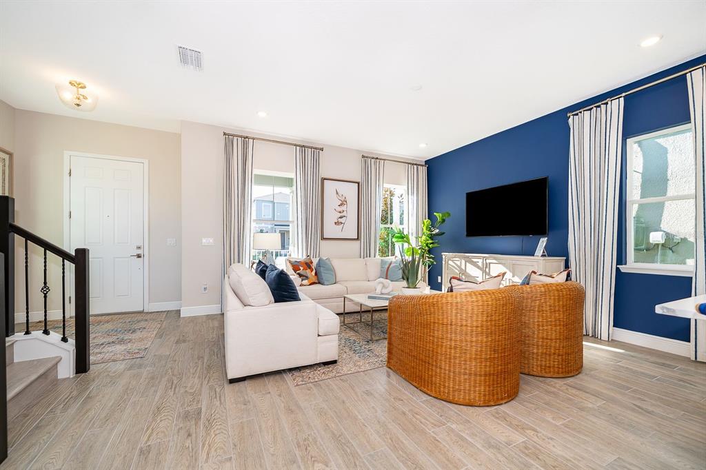 A living room features a blue accent wall, white sofa, and two wicker armchairs — 13006 SERENE GLADE ROAD, WINTER GARDEN, FL