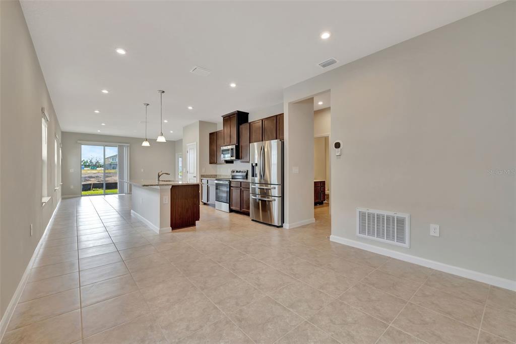 An open-concept kitchen features dark wood cabinets, stainless steel appliances, and tile flooring — 4525 PIPPIN LANE, LAKEWOOD RANCH, FL