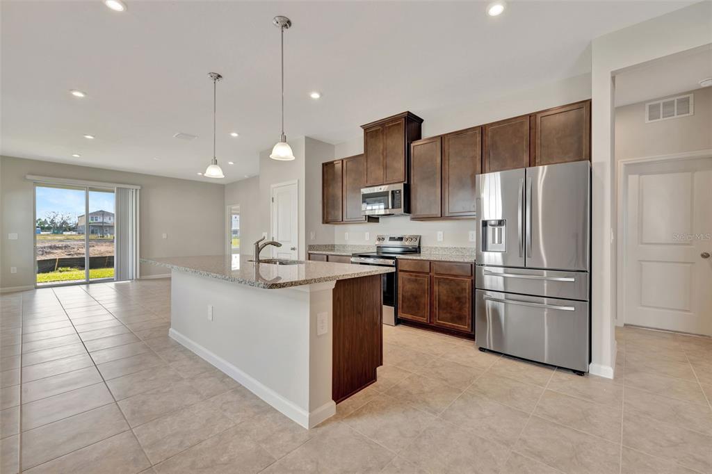 A kitchen features dark wood cabinets, granite countertops, stainless steel appliances, and a center island — 4525 PIPPIN LANE, LAKEWOOD RANCH, FL