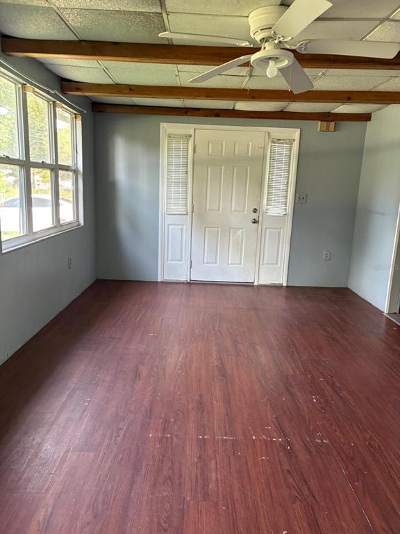 A room with wood-look flooring, a ceiling fan, exposed wooden beams, and a white door — 110 VALENCIA STREET, WINTER HAVEN, FL
