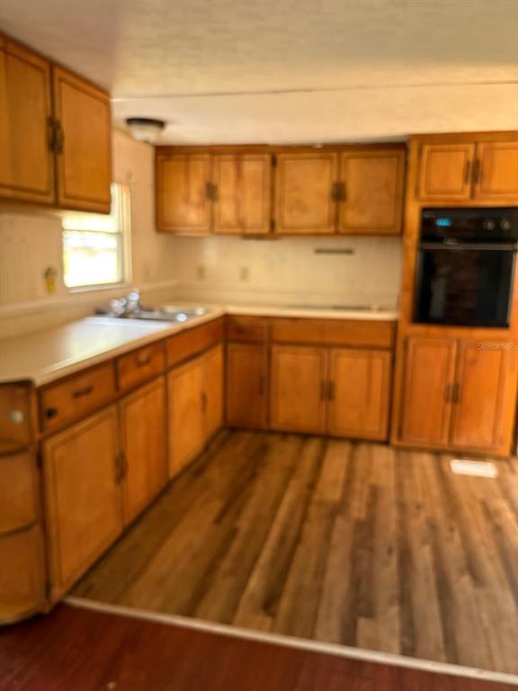 A kitchen with wood cabinets, a built-in oven, and wood-look flooring — 110 VALENCIA STREET, WINTER HAVEN, FL