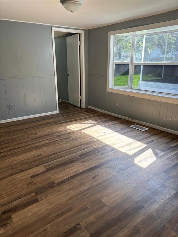 An empty room with gray paneled walls, wood-look flooring, and a large bay window — 110 VALENCIA STREET, WINTER HAVEN, FL
