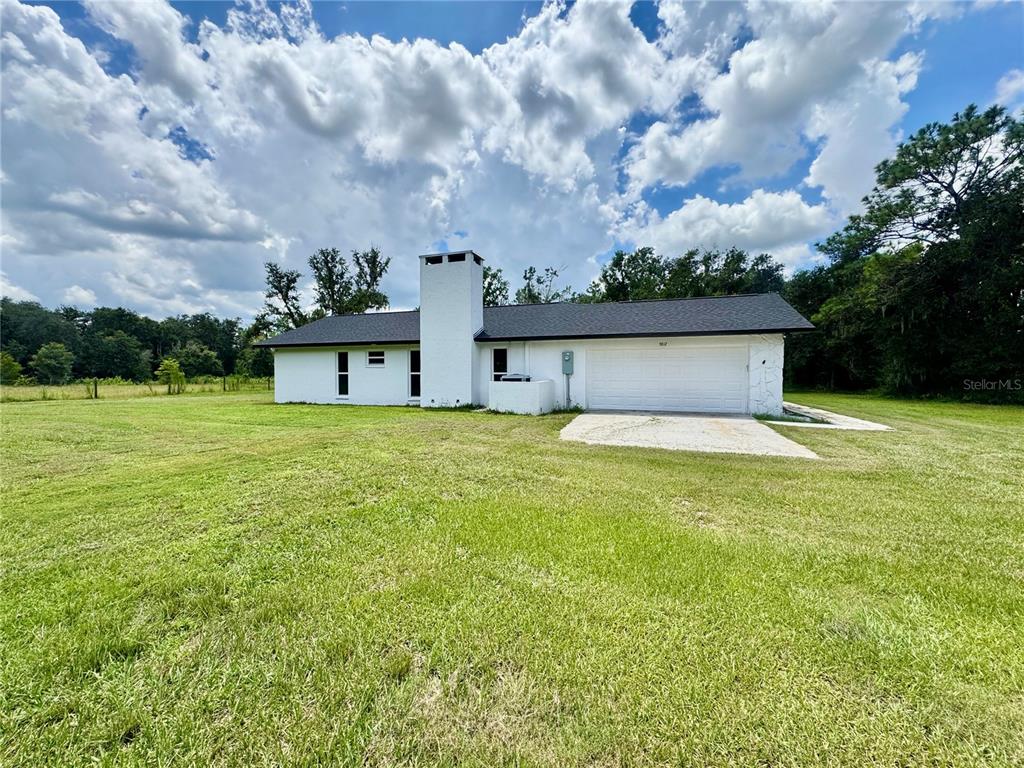 A white single-story house with a large chimney and a two-car garage sits on grass — 5812 N DORMANY ROAD, PLANT CITY, FL