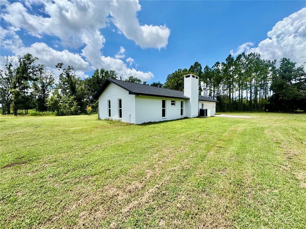 A white, single-story house with a black roof and a prominent chimney stands in a field — 5812 N DORMANY ROAD, PLANT CITY, FL