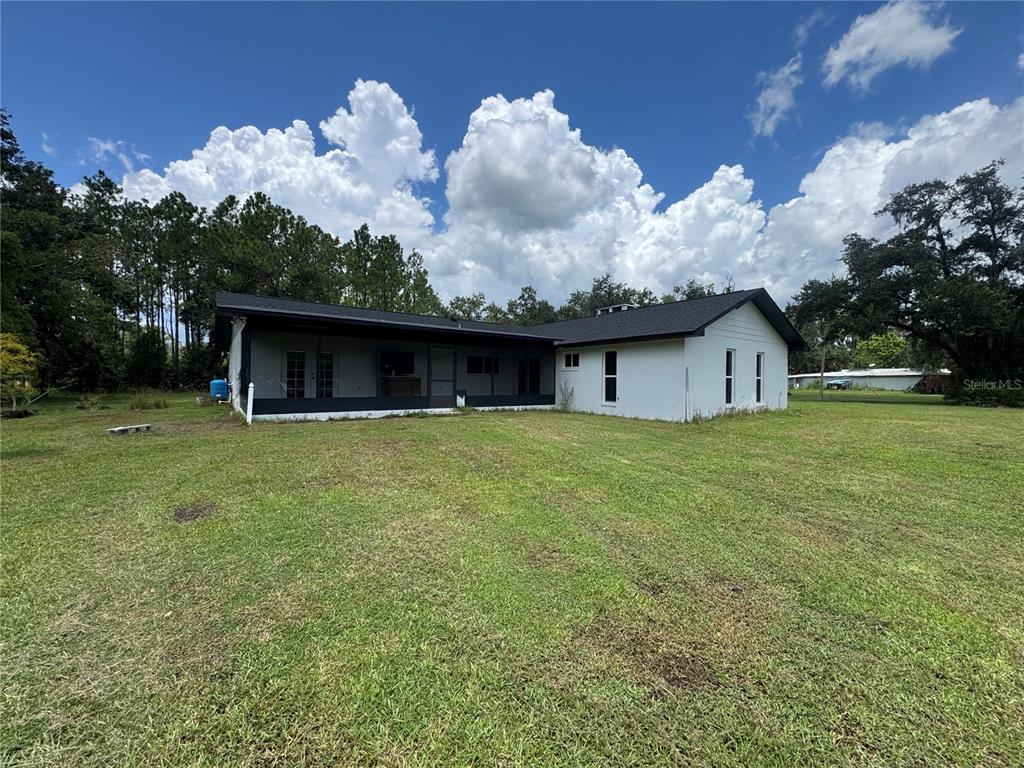 A white house with a black roof and a screened-in porch sits on a grassy lot — 5812 N DORMANY ROAD, PLANT CITY, FL