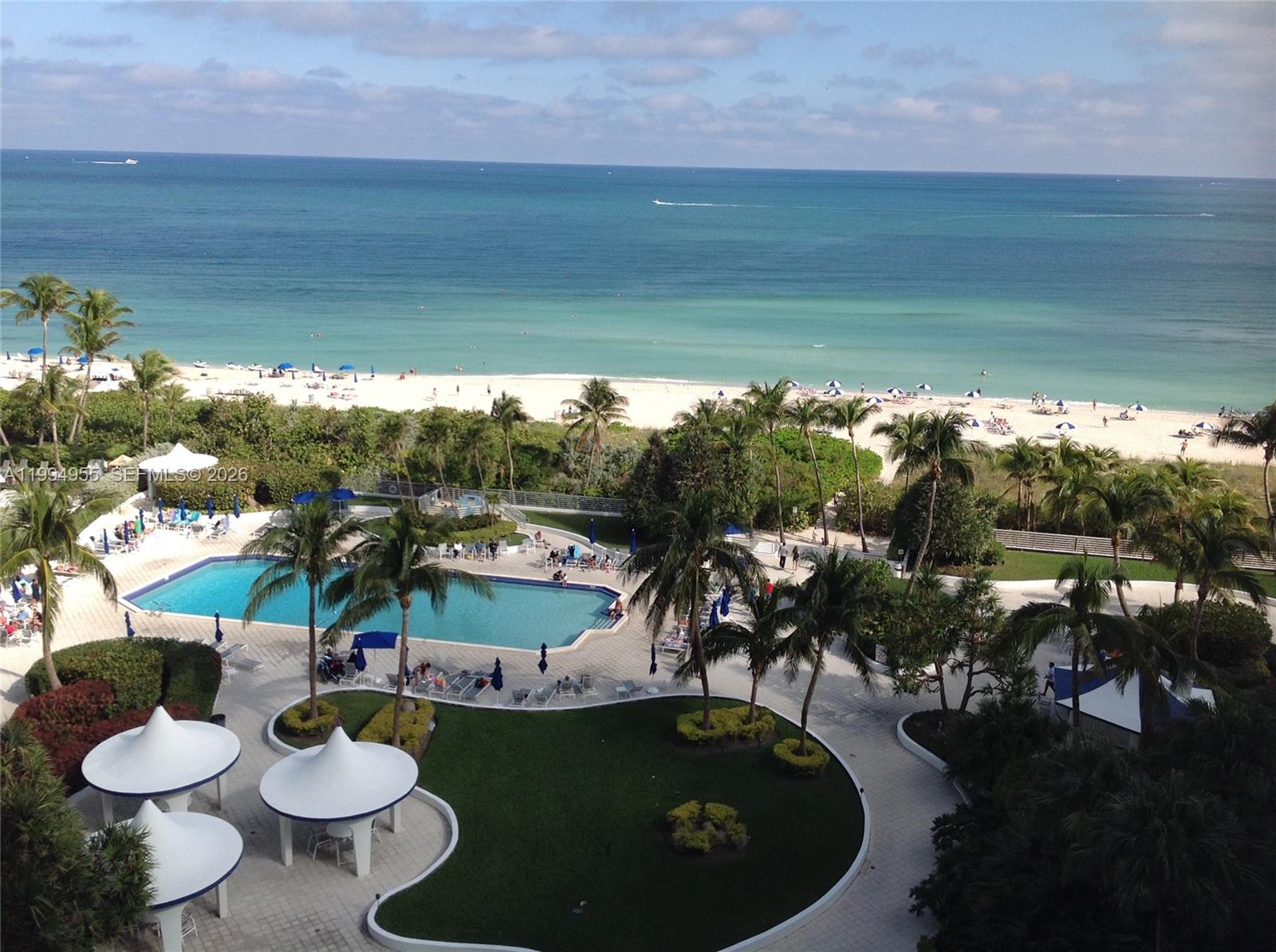 An elevated view of a resort swimming pool, palm trees, and a sandy beach — 5151 Collins Ave # 1119, Miami Beach FL 33140, MIAMI BEACH, FL