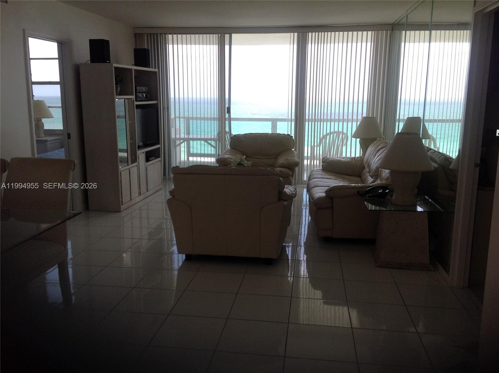 A living room with tile floors, white leather furniture, and a balcony overlooking the ocean — 5151 Collins Ave # 1119, Miami Beach FL 33140, MIAMI BEACH, FL