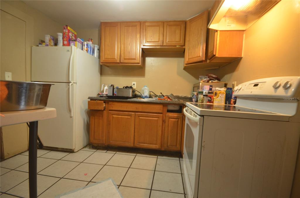 A kitchen features wood cabinets, a white refrigerator, a white stove, and tiled flooring — 1607 E NOME STREET, TAMPA, FL