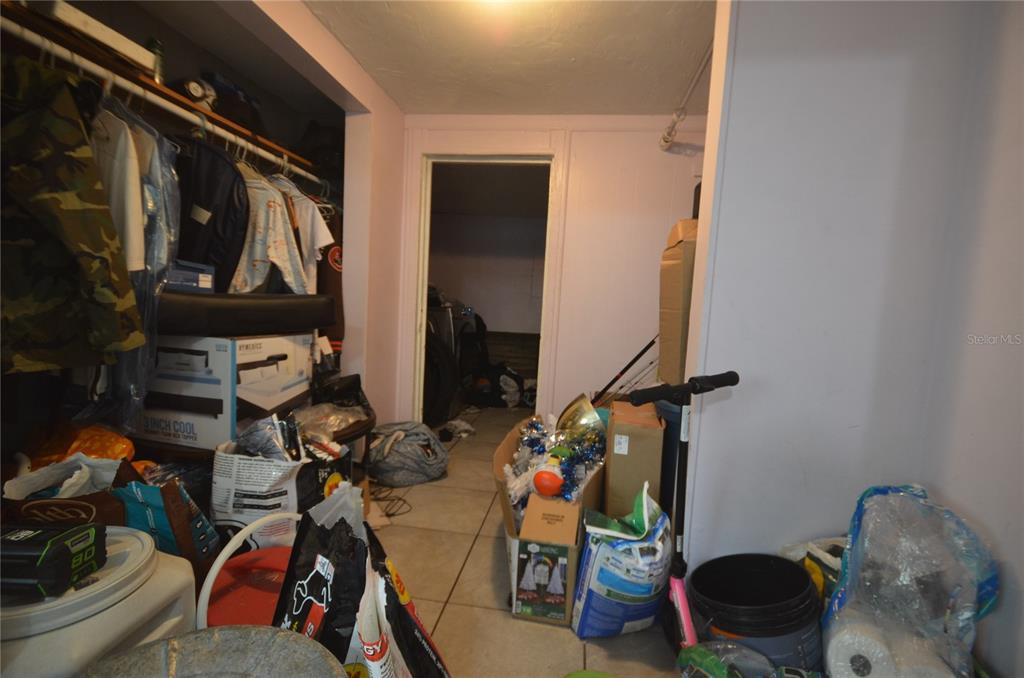 A cluttered storage room with a closet, tile flooring, and a doorway leading to another space — 1607 E NOME STREET, TAMPA, FL