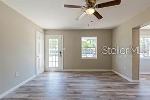 An interior view of a room with light-colored walls, wood-look flooring, and a ceiling fan — 3410 ALOHA DRIVE, SARASOTA, FL