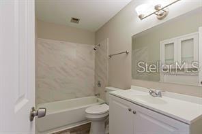 A bathroom features a white vanity, a toilet, and a shower-tub combination with tiled walls — 3410 ALOHA DRIVE, SARASOTA, FL